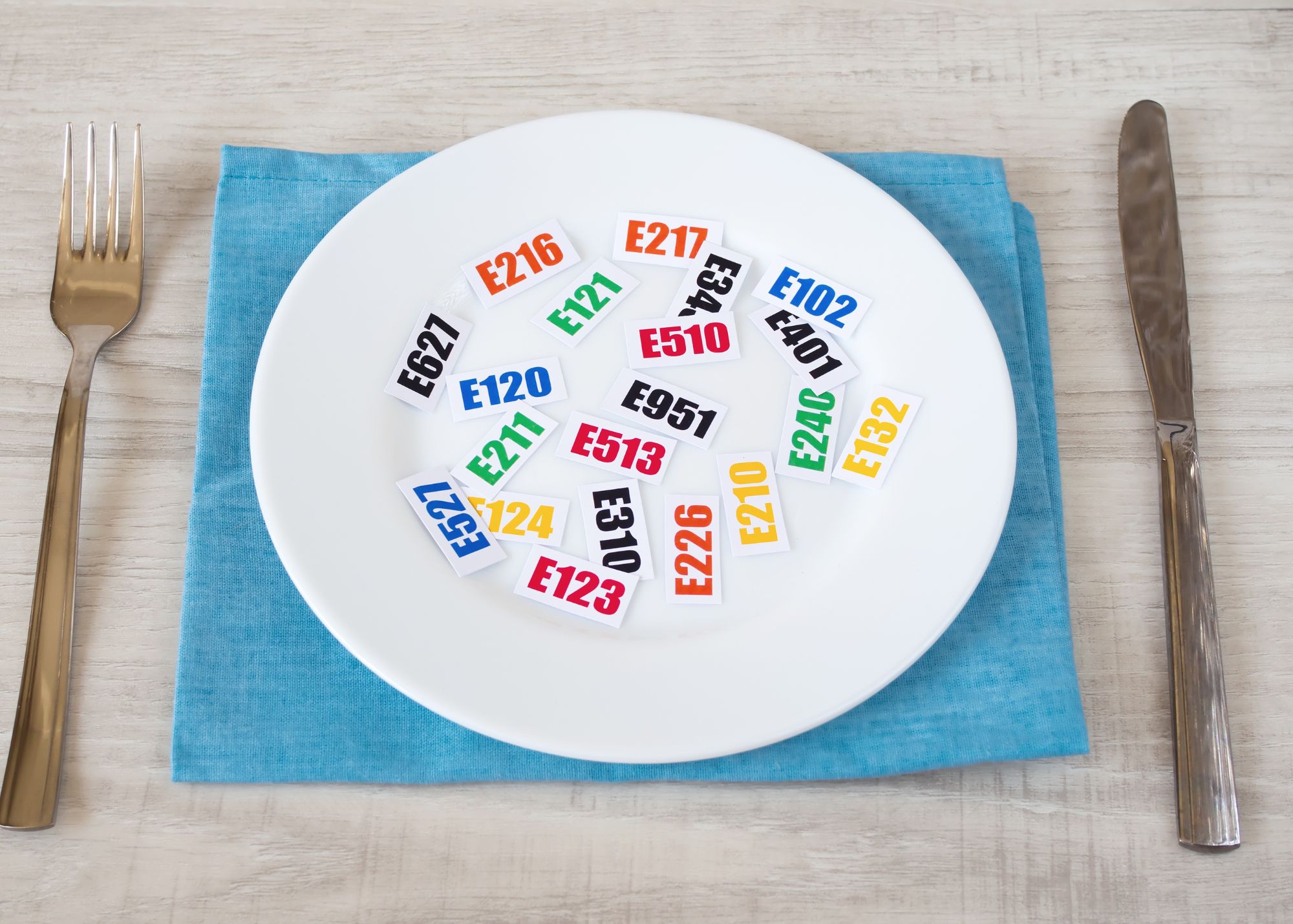 Numery chemicznych dodatków w żywności na kolorowych kartkach leżące na talerzu