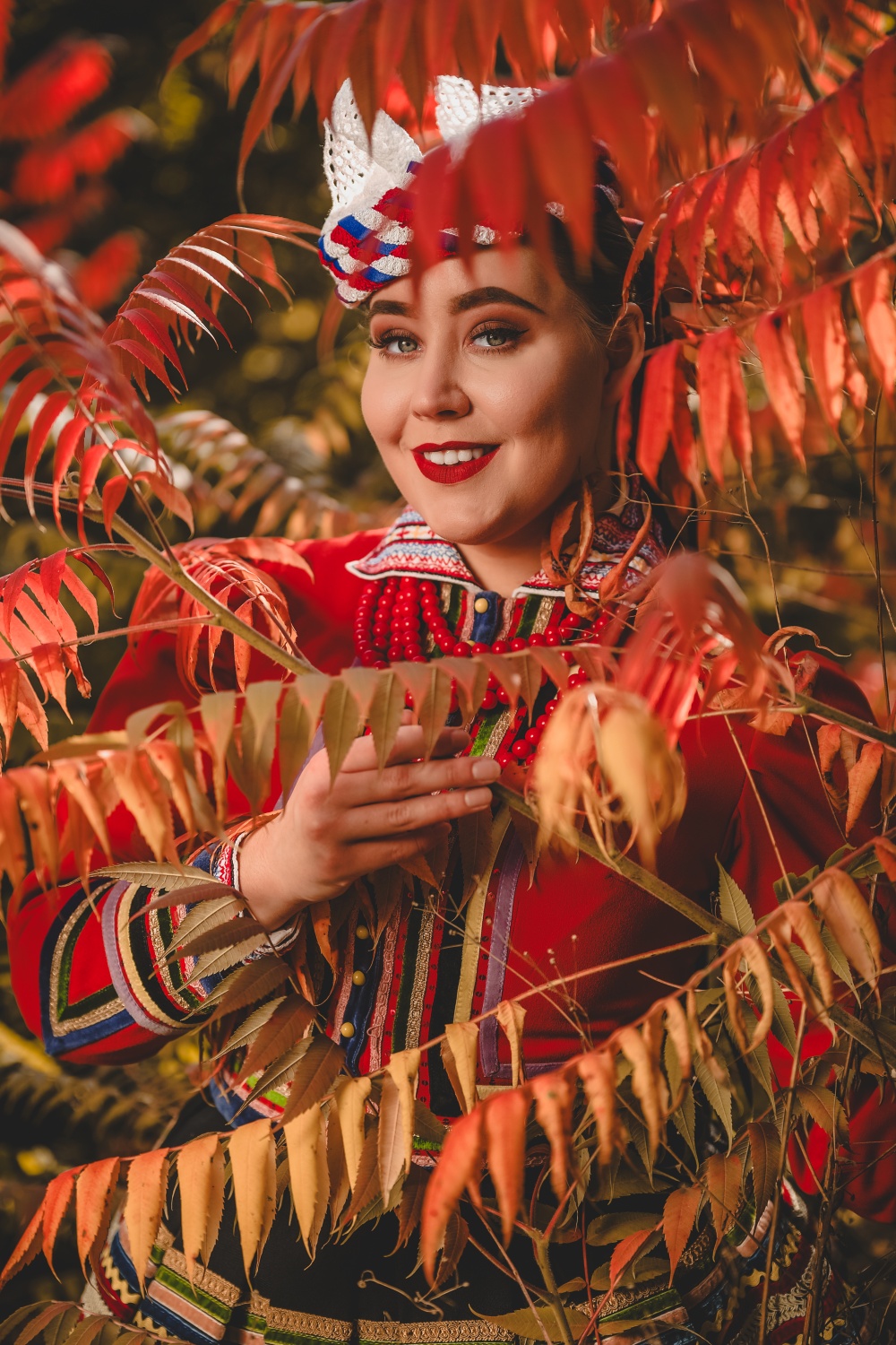 Kobieta w stroju ludowym wśród jesiennych liści