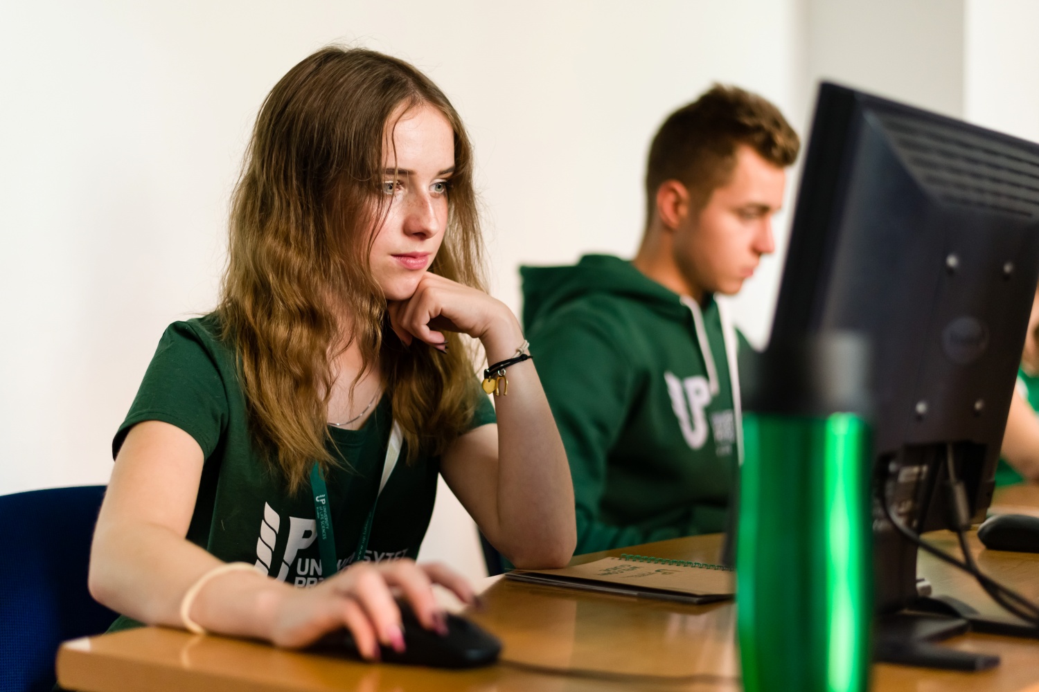 studenci w koszulkach z logo UP w Lublinie podczas pracy przy komputerach