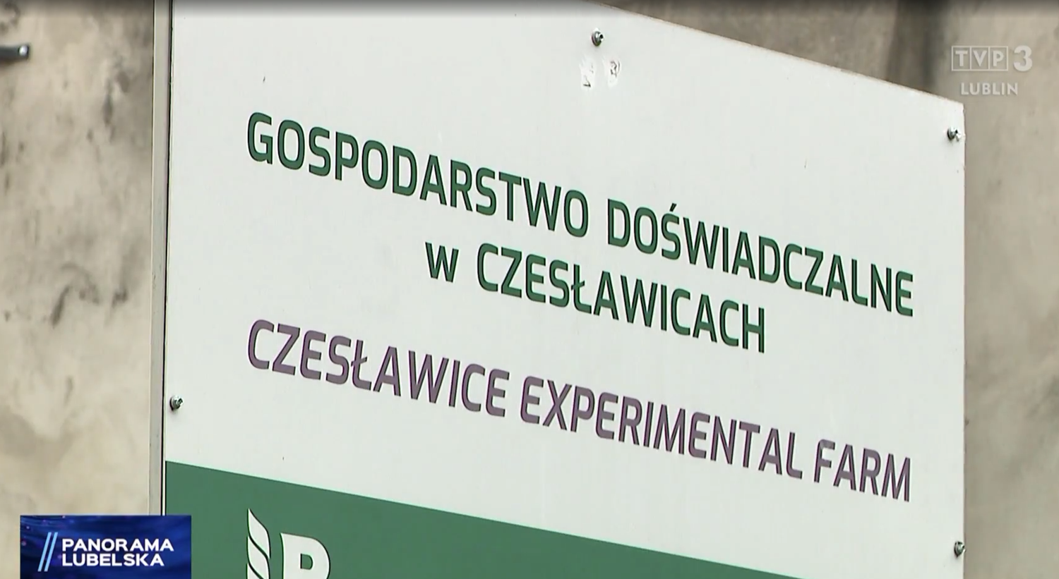 Biała tablica informacyjna z napisem:  Gospodarstwo Doświadczalne w Czesławicach/Czesłąwice Experimental Farm