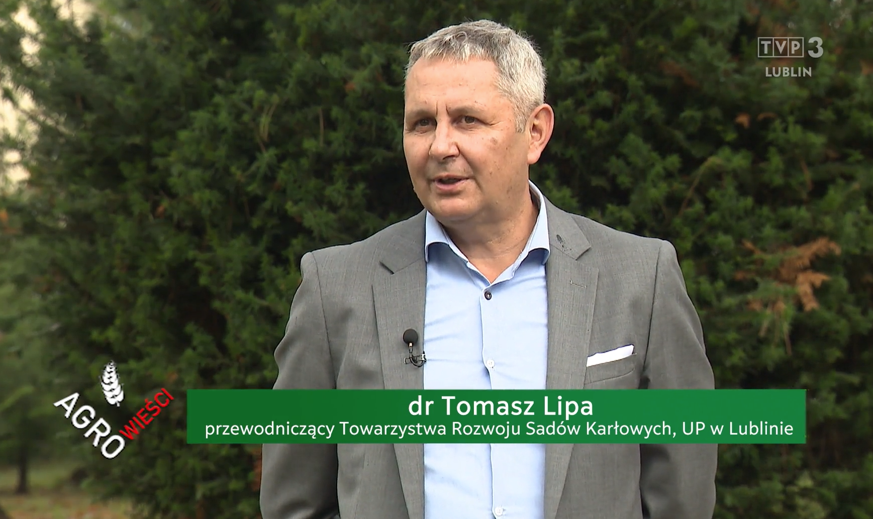 dr Tomasz Lipa - szpakowaty mężczyzna w szarym garniturze, w tle - drzewa
