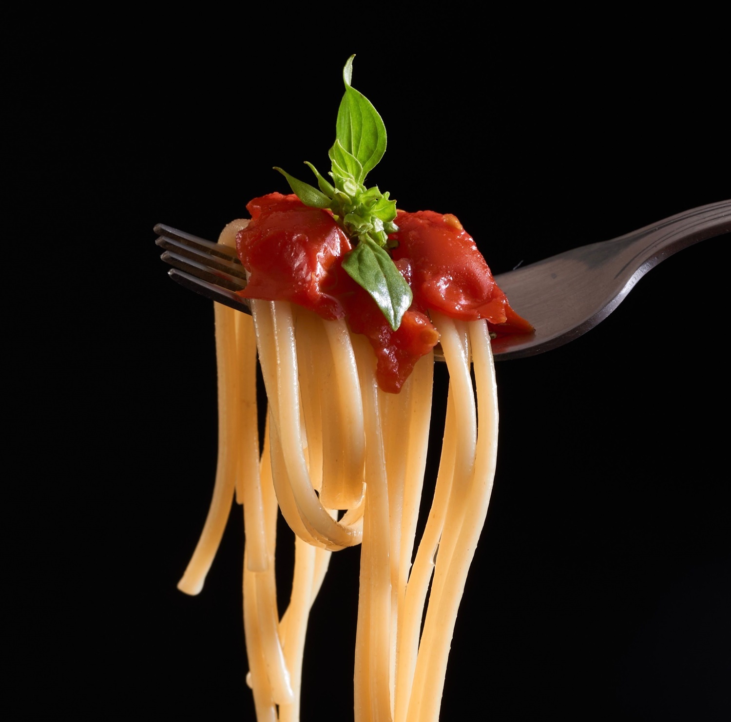 spaghetti polane sosem pomidorowym, posypane bazylią, tło-czarne