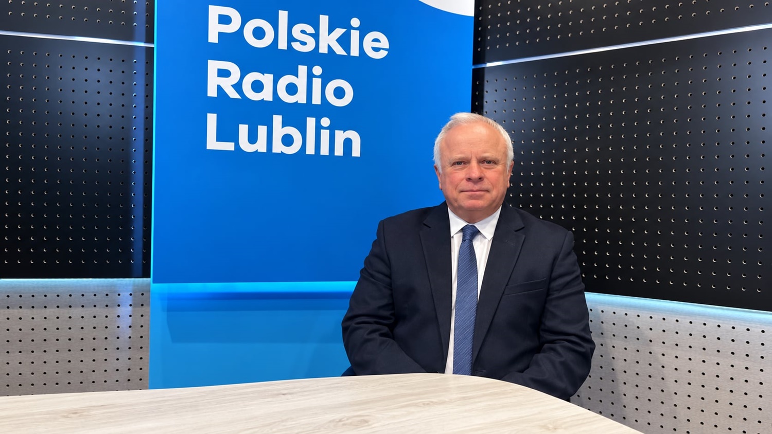 rektor Krzysztof Kowalczyk siedzi na niebieskim tle z&nbsp;baiłym napisem Polskie Radio Lublin, obok czarne panele ścienne